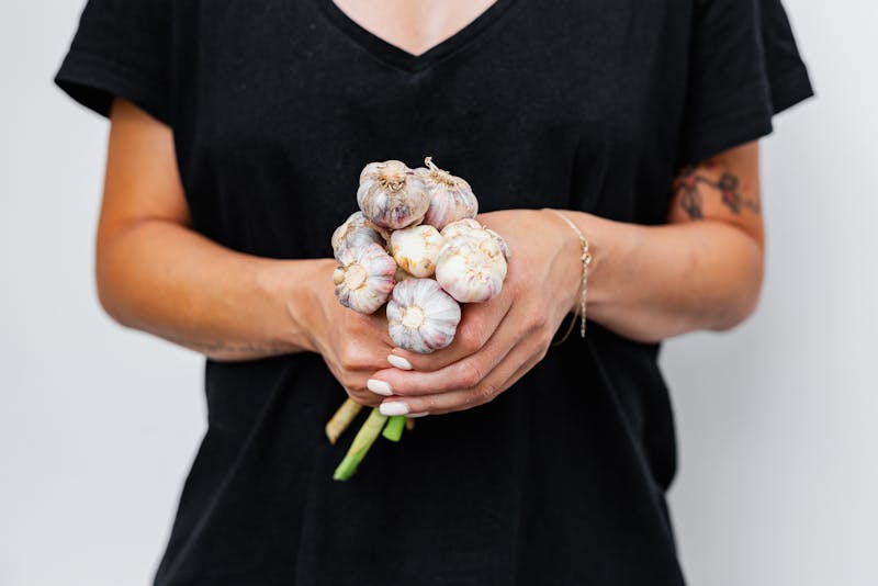 a woman in black dress is holding garlic bulbs 