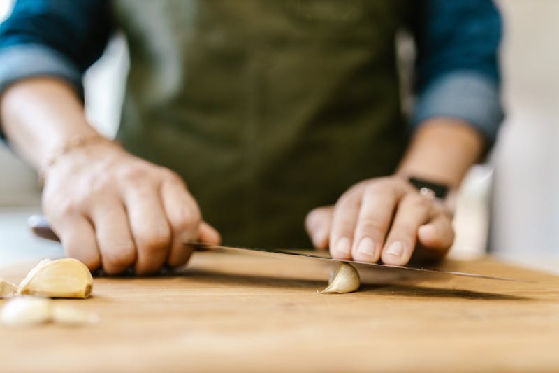 crushing garlic cloves on chopping board