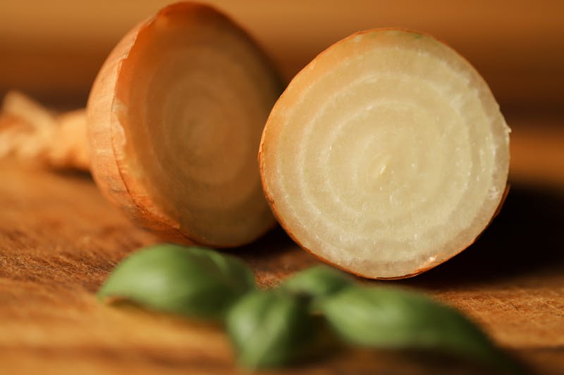 Close-up of a halved onion with a fresh basil leaf