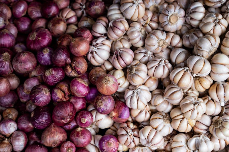 Multiple garlic bulbs and red onions together