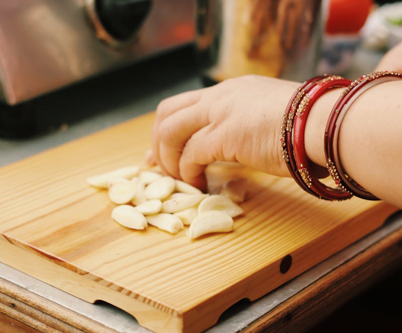 woman is cutting garlic on a board