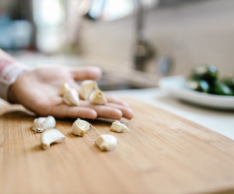garlic cloves in hand and chopping board