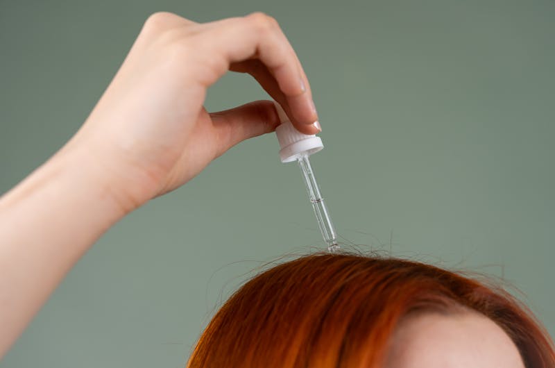 Applying garlic oil with a dropper to the scalp on hair