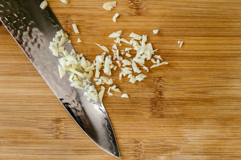raw chopped garlic cloves with knive on chopping board