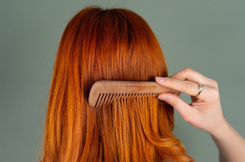 Red-haired woman combing her hair with a comb