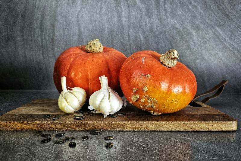 Garlic bulbs and pumpkins on a wooden cutting board