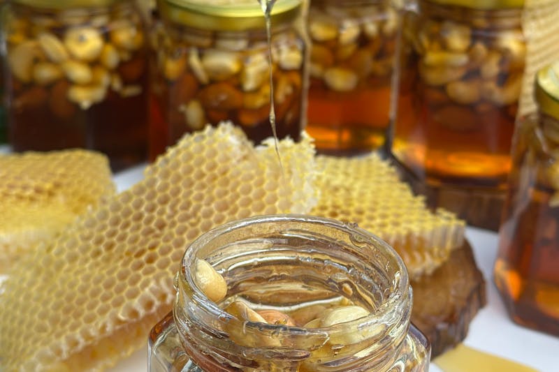 honey flowing into a jar with honeycomb pieces