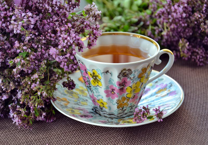 a cup of fresh lemon balm tea and purple flowers in the background